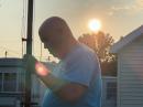 Corey Landrum, KB4YPN, adjusts a DX Commander vertical antenna while the sun rises behind him.