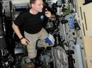 Floating in microgravity, ISS Expedition 25 Commander Doug Wheelock, KF5BOC, speaks to Earth via ham radio from NA1SS. The transceiver control head is just visible on the cluttered bulkhead, with operating instructions posted conveniently adjacent. All gear is secured, so it doesn’t float around the cabin. [NASA Photo]